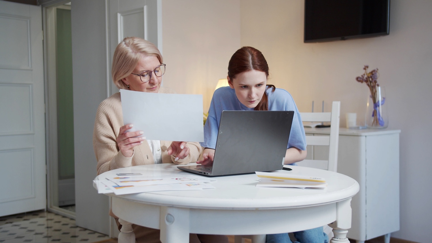 A woman helps her grandmother with work. They study documents and fill out tables on the computer. High quality 4k footage